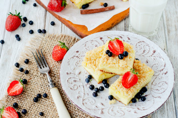 
rustic grated cheese cake with berries , with strawberries , blueberries and milk on a wooden background