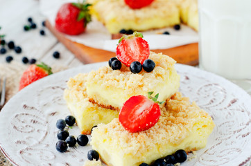 
rustic grated cheese cake with berries , with strawberries , blueberries and milk on a wooden background