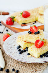 
rustic grated cheese cake with berries , with strawberries , blueberries and milk on a wooden background