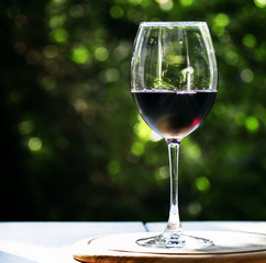 Glass of cold red wine, bouquet of red roses, on a café terrace