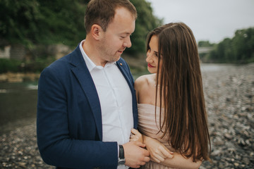 Fototapeta premium Young cute couple honeymoon posing and holding their hands on dating in a beautiful place italy near ocean and mountains, hug, smile and talk to each other 