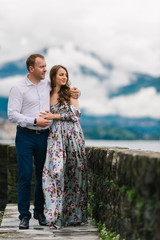 Young cute couple honeymoon walks holding their hands on dating in a beautiful place italy near ocean and mountains, hug, smile and talk to each other