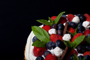 Biscuit homemade cake with cream and berries on black background