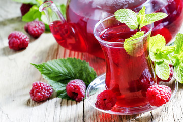 Summer raspberry tea with mint in a glass, vintage wooden backgr