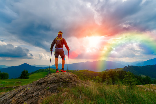 Man in the mountains at sunset with rainbow