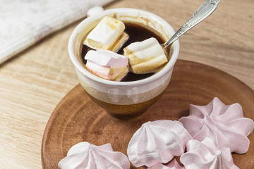 Fototapeta na wymiar Chewing marshmallows, meringue and coffee cup on a wooden board