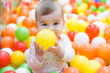 Fototapeta na wymiar Beautiful baby girl playing with colorful balls