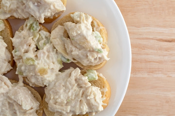Chicken salad on small pieces of French bread atop a wood table.