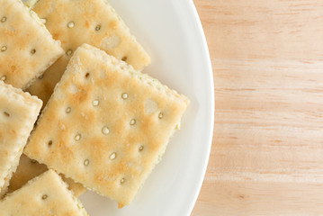 Cream cheese and chives crackers on a white plate atop a wood table top close view.