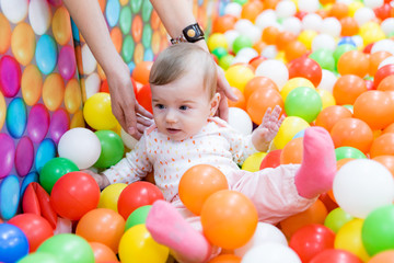 Beautiful baby girl playing with colorful balls