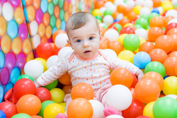 Beautiful baby girl playing with colorful balls
