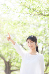 Fototapeta premium 指差しをする女性、新緑