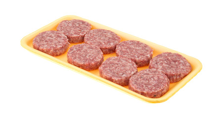 Sausage patties in a foam tray on a white background side view.
