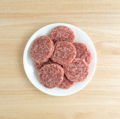 Sausage patties on a white plate atop a table top view.