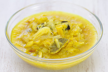 cod fish curry in bowl on white wooden background