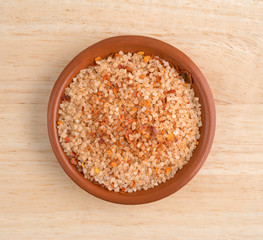 Small dish filled with salt, red chili pepper and paprika on a wood table top view.