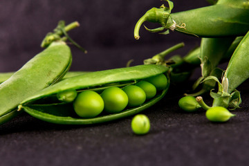 fresh green sweet peas  on black stone background