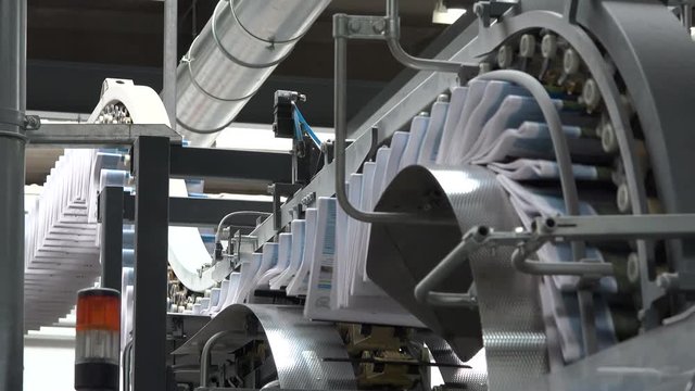 close shot of newspapers printed and transported on chain