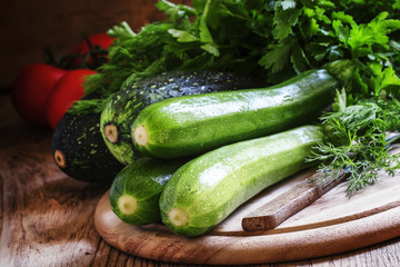 Small green zucchini on the wooden cutting board, selective focu