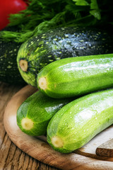Small green zucchini on the wooden cutting board, selective focu