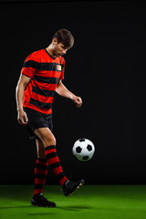 Soccer player kicking ball over black background