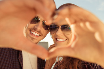Cheerful romantic couple making heart gesture with hands