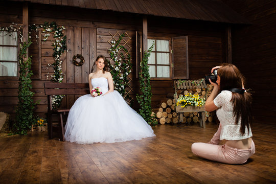 Young sexy woman photographer is taking pictures the bride in the studio