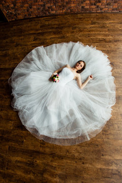 Young sexy bride in the studio is lying on the wooden floor