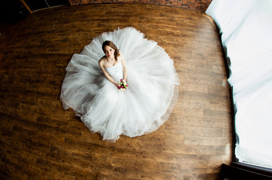 Young sexy bride in the studio is sitting on the wooden floor