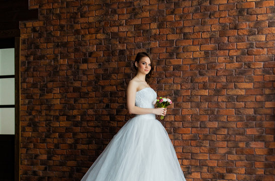 Young sexy bride in a studio standing next to the wall
