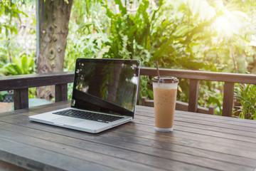 Laptop Notebook with iced coffee cup on wooden table