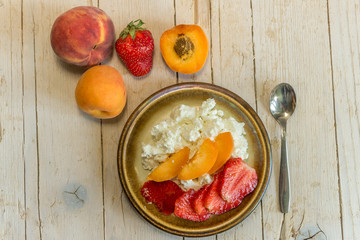 Творог с фруктами и клубникой на деревянном фоне. Здоровое питание.