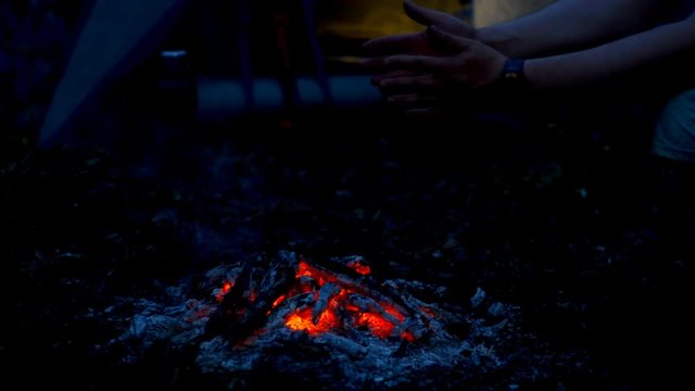 Tourist warming his hands over the campfire.