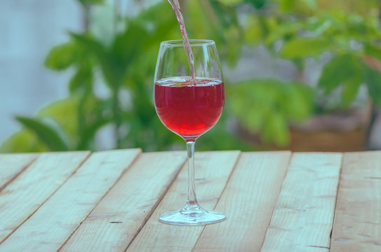 Pouring black currant juice in glass on wood table