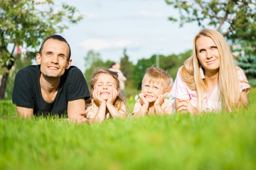Fototapeta premium Portrait of happy parents with kids lying at the park
