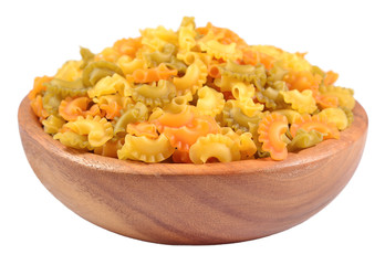Colored uncooked italian pasta in a wooden bowl on a white