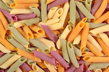 Colored uncooked italian pasta penne as background