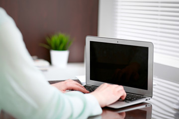 Fototapeta premium Business woman hands in a green blouse sitting at the desk in the office and typing on the laptop .