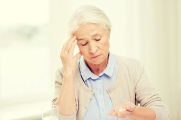 senior woman with water and medicine at home