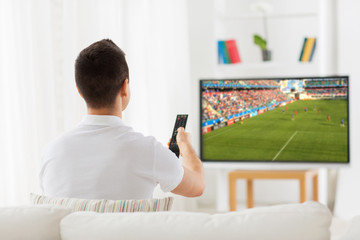 man watching football or soccer game on tv at home