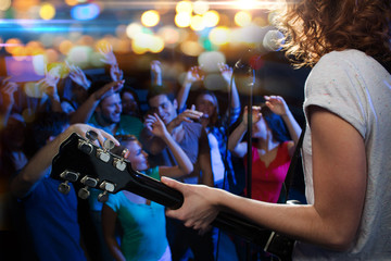 female singer playing guitar over happy fans crowd