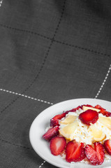 Sliced strawberries with lemon is lying on delicious cottage cheese. Cottage cheese is lying on a plate with slices of strawberries.