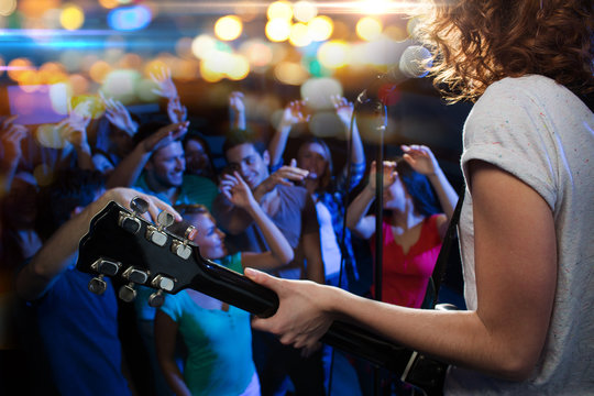 Female Singer Playing Guitar Over Happy Fans Crowd