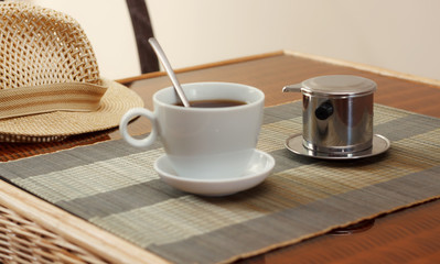 Morning coffee served in vietnam coffee filter on rattan table, natural light photo