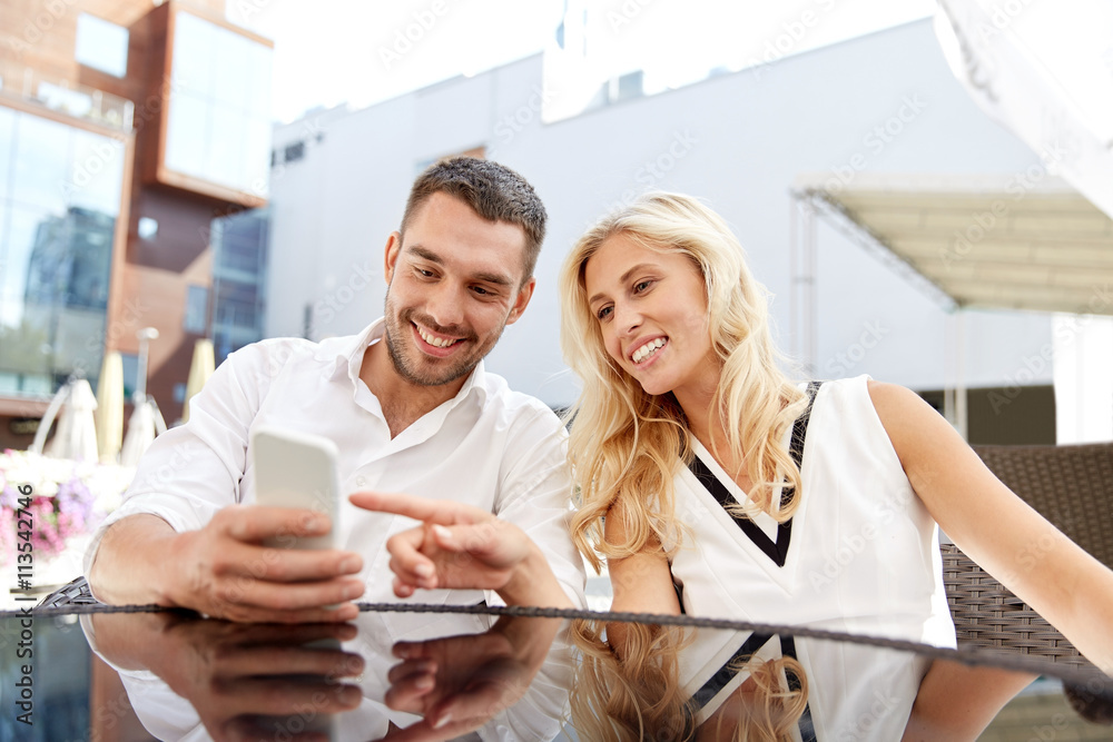 Wall mural happy couple with smatphone at restaurant terrace