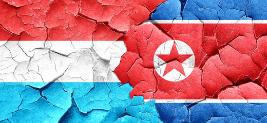 Luxembourg flag with North Korea flag on a grunge cracked wall