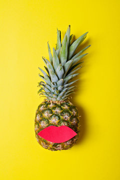 Pineapple with red lips on yellow background