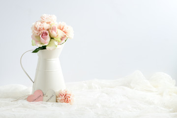 Mockup styled stock image of carnations and roses in a cream jug with a piece of lace. You can place your business promotion, blog title, quote, headline or image in the space beside the jug.