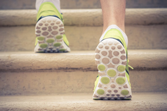 Close Up Of Male Athlete Feet With Sneakers Running Up The Stairs. Rear Side View. Sport, Fitness, Jogging, Workout And Healthy Lifestyle Concepts.