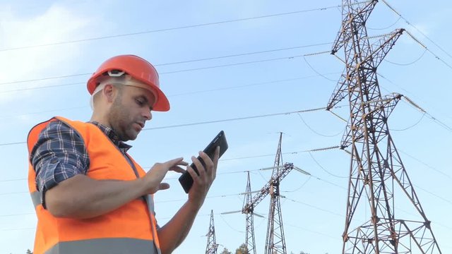 Electrical engineer working. Talking on the phone and working on the tablet.Checking the power grids.